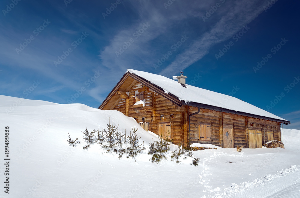 Alpine chalet surrounded by fresh snow on a beautiful sunny day.