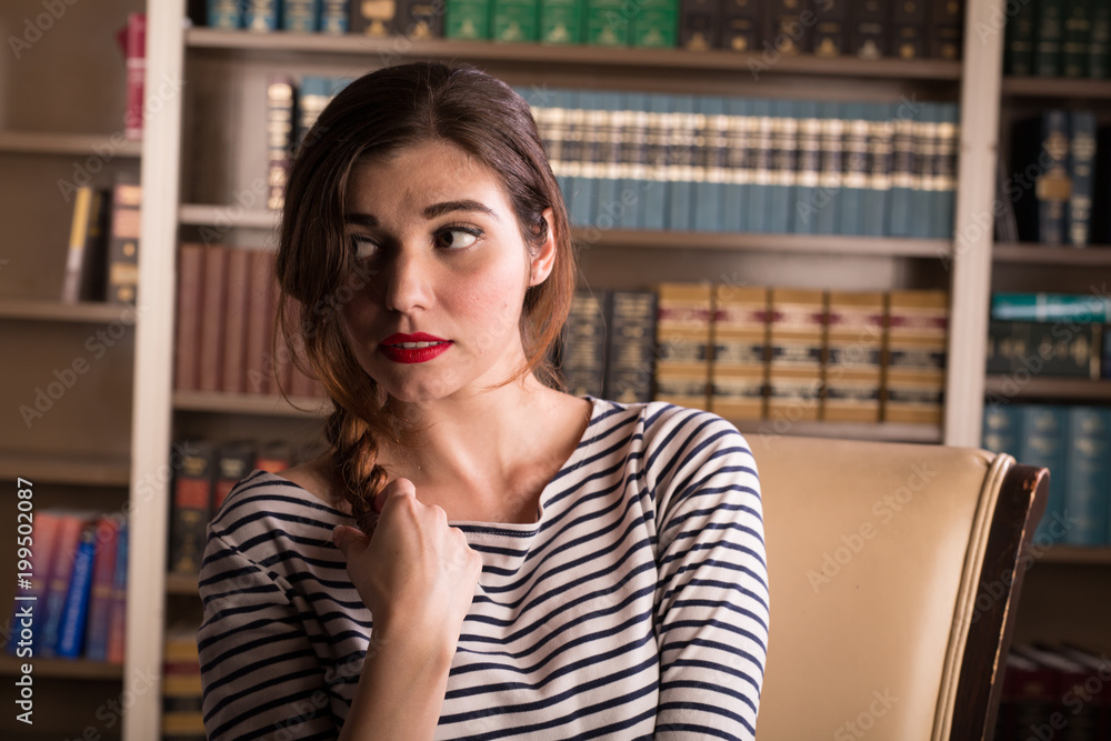 Young caucasian woman dressed in mid century casual fashion poses in a library Young caucasian woman dressed in mid century casual fashion poses in a library