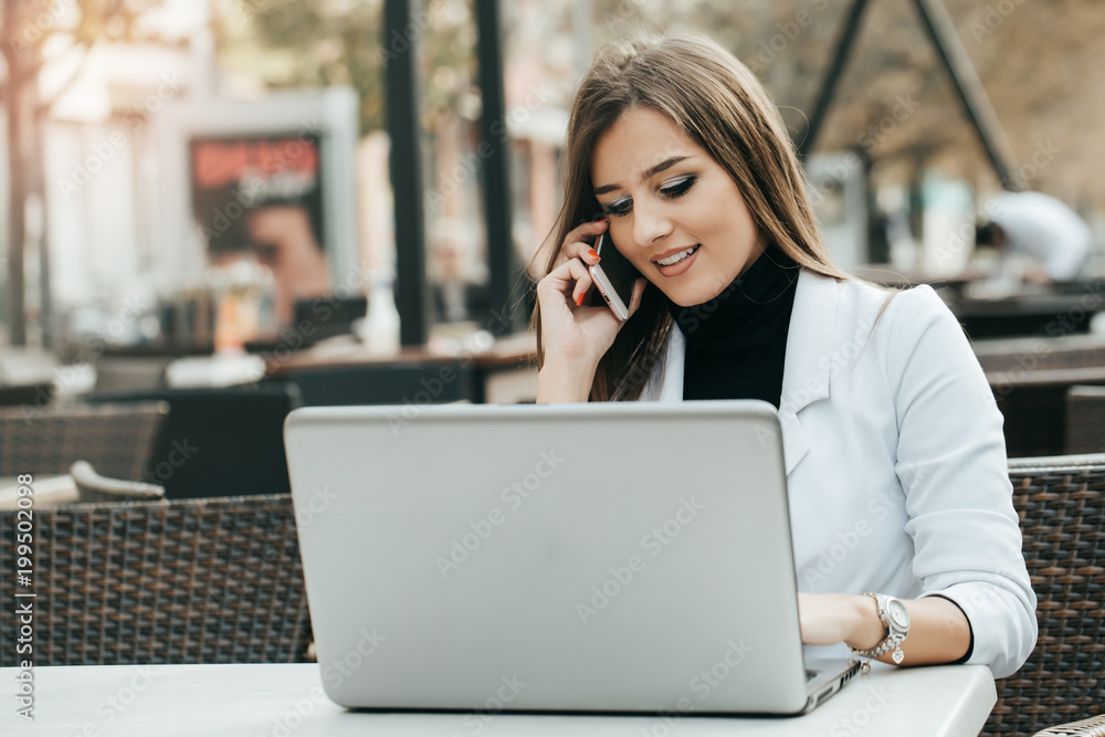 Woman working with a phone and laptop Woman working with a phone and laptop