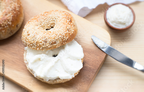  Bagel with spread cream cheese close-up on a wooden cut board. Slie of Delicious bagel, golden bake color, soft inside, crispy outside, taste perfect combination with salmon,peanut butter,chocolate. photo