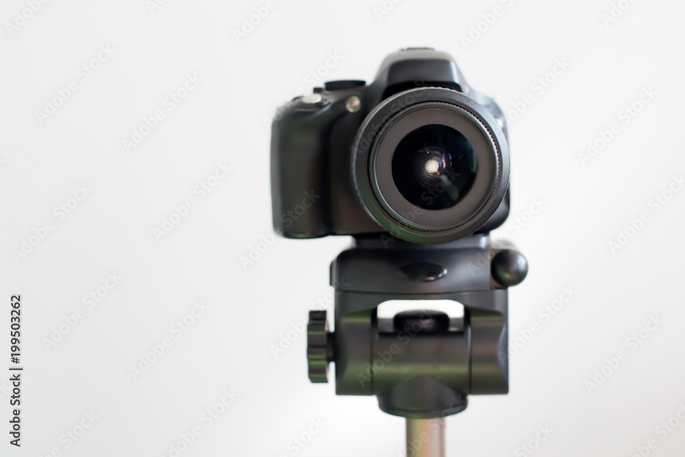 Professional black DSLR mirrorless camera on tripod on white background. Blogging and video recording or photo shooting.