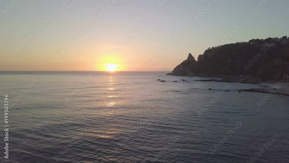 Costa sabbiosa del mare calmo vicino a costa frastagliata con scogli al pomeriggio vicino al tramonto Costa sabbiosa del mare calmo vicino a costa frastagliata con scogli al pomeriggio vicino al tramonto