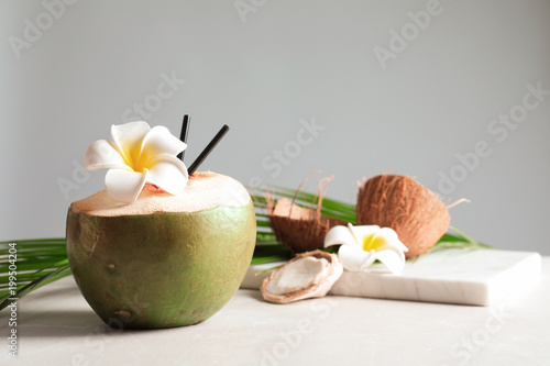 Beautiful composition with fresh green coconut on table against gray background