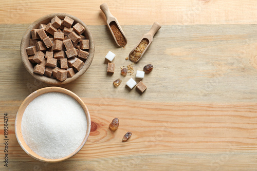 Various kinds of sugar in bowls on wooden background