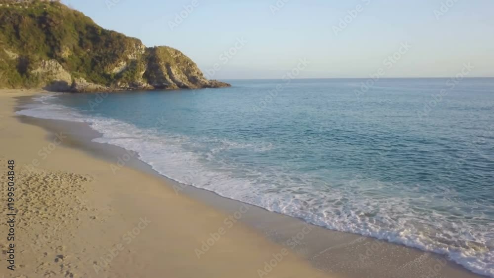 Costa sabbiosa del mare calmo vicino a costa frastagliata con scogli al pomeriggio vicino al tramonto Costa sabbiosa del mare calmo vicino a costa frastagliata con scogli al pomeriggio vicino al tramonto