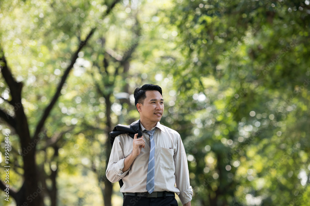 Young Asia businessman happy face. He was walking in the Park. Young Asia businessman happy face. He was walking in the Park.
