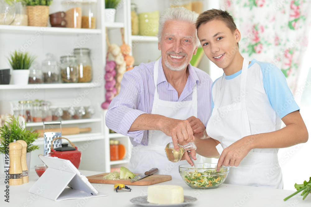 Senior man with grandson preparing dinner in kitchen Senior man with grandson preparing dinner in kitchen