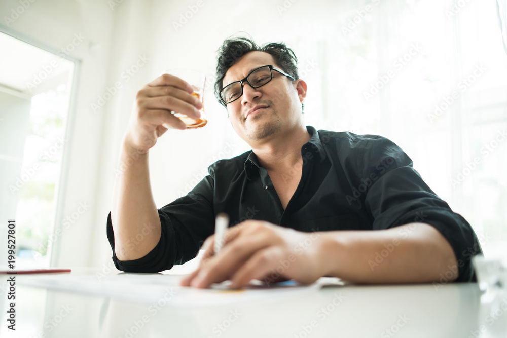 Businessman sitting in a business center bar smoking cigar and drinking whiskey