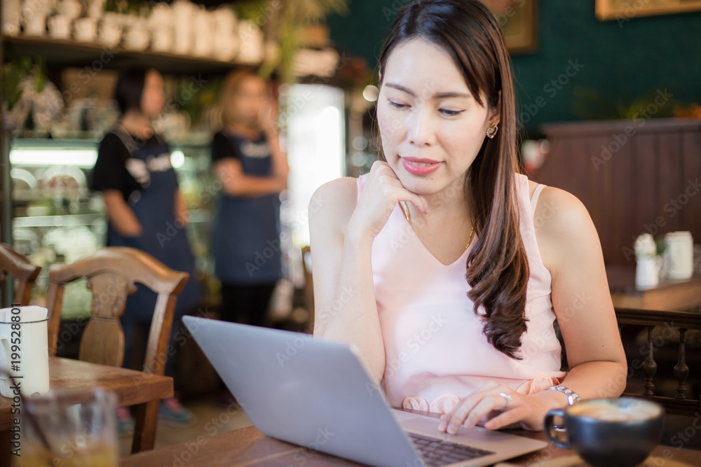 Business women sitting in cafe using laptop and drinking hot coffee
