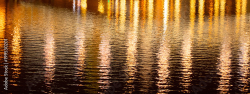 Light of lanterns on the smooth surface of water at night as a background
