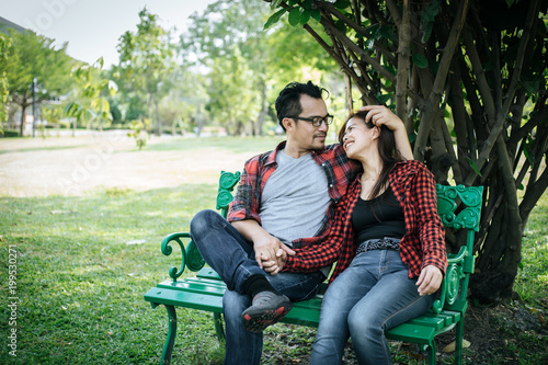 Young couple in nature sitting on bench, male and female together