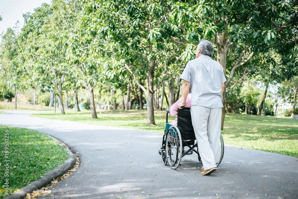 Senior man caring for disabled wife in his wheelchair. Senior man caring for disabled wife in his wheelchair.