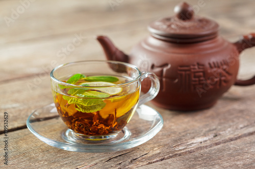 cup of black tea with mint leaves on a wooden table