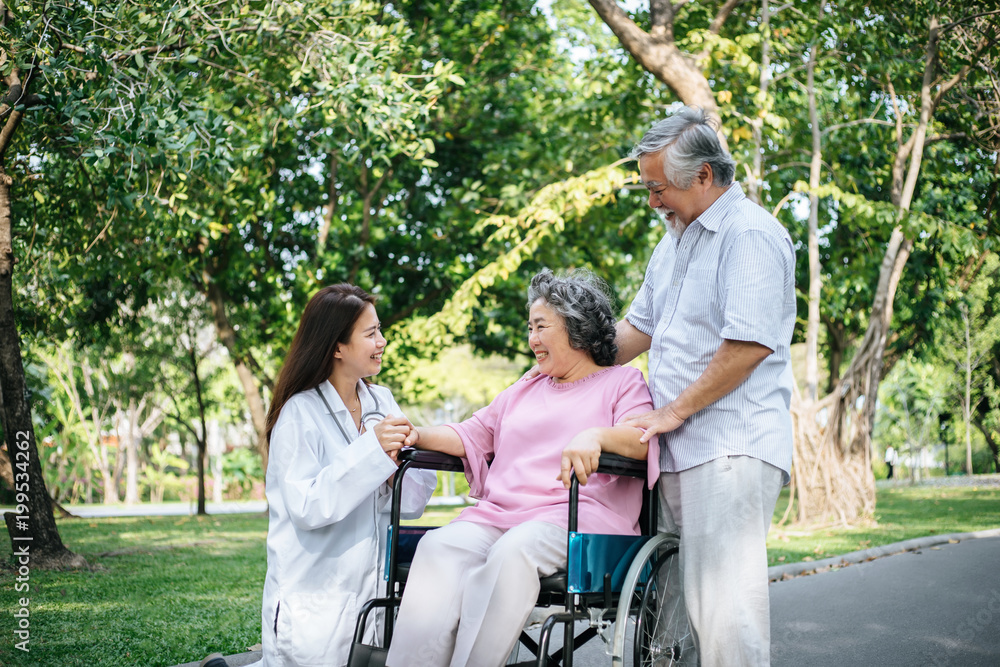 Nurse looking at elderly patient in a wheelchair. Doctor talking to old disabled Nurse looking at elderly patient in a wheelchair. Doctor talking to old disabled
