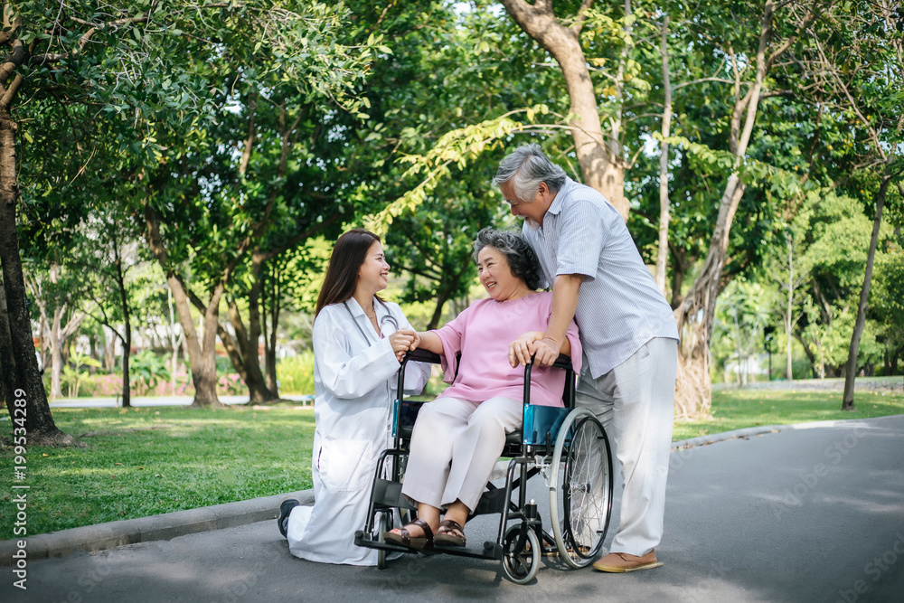 Nurse looking at elderly patient in a wheelchair. Doctor talking to old disabled Nurse looking at elderly patient in a wheelchair. Doctor talking to old disabled