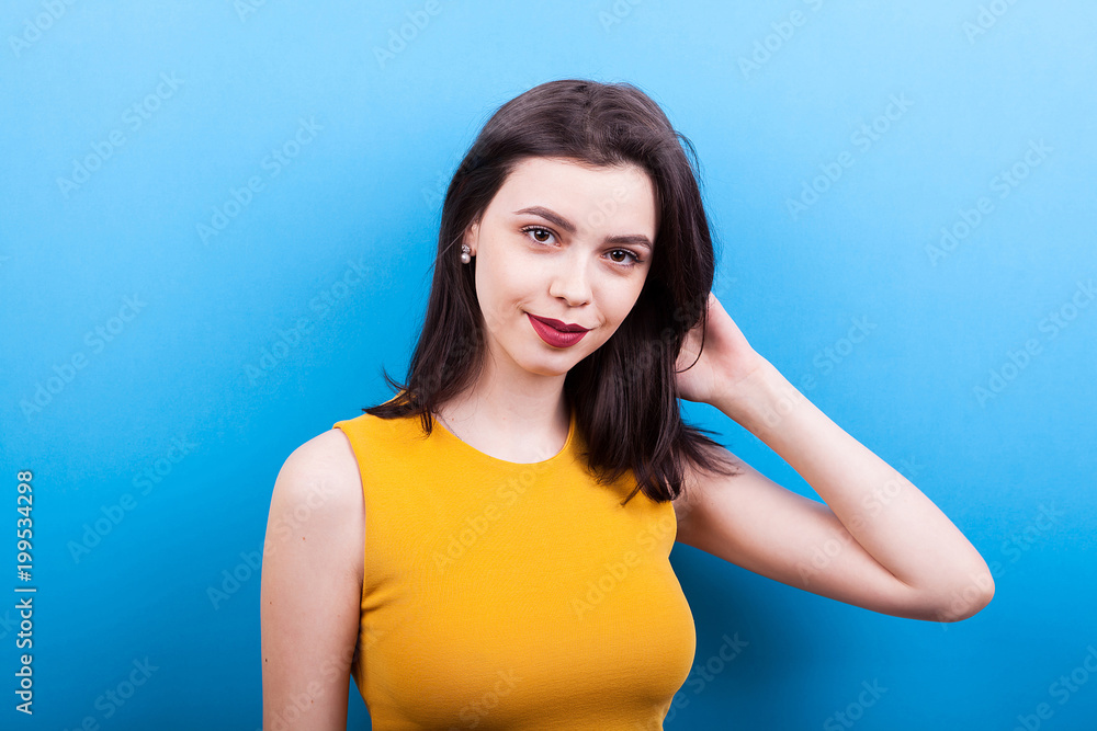 Smiling beautiful woman looking at the camera on blue background Smiling beautiful woman looking at the camera on blue background
