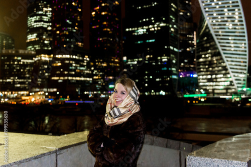 Young beautiful girl walking in night city. View of Moscow on the background.