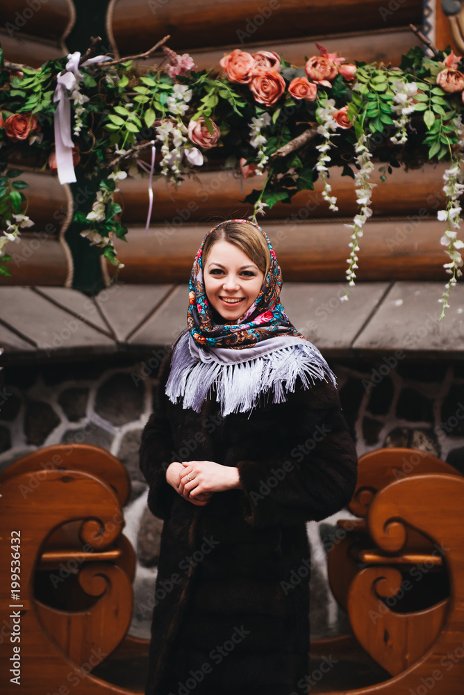 A young beautiful girl in a mink coat and a Russian folk scarf walks around the Izmailovo Kremlin. Moscow, Russia.