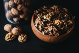 Walnuts kernels in wood bowl on dark desk, Walnut with color background, Whole walnuts in wood vintage bowl. rustic