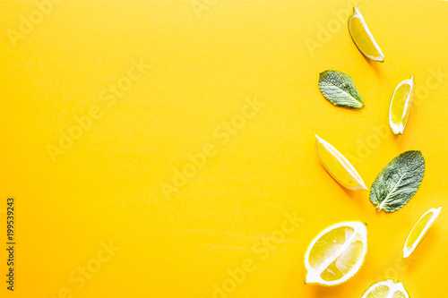 Pieces of lemon, lime and green mint leaves on a yellow background. Summer products for making lemonade. Top view, flat lay, copyspace
