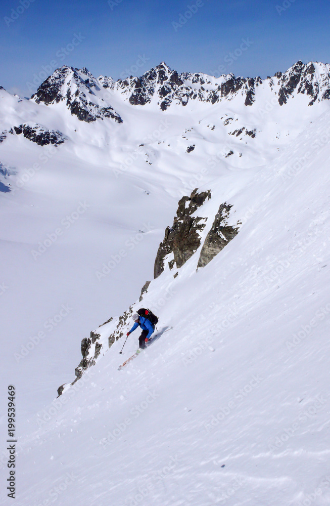 male extreme skier skiing down a very steep couloir in deep winter in the Swiss Alps near Klosters