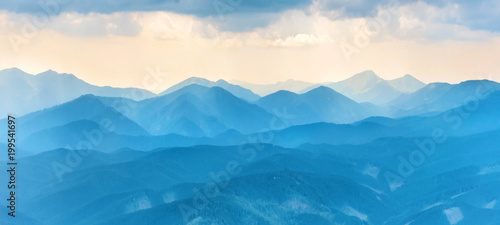 Panorama with sunset in blue mountains. Landscape view of peaks ridge