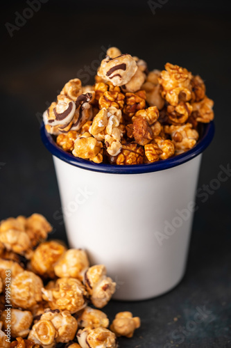 A variety of Popcorn in a white cup on a dark background.