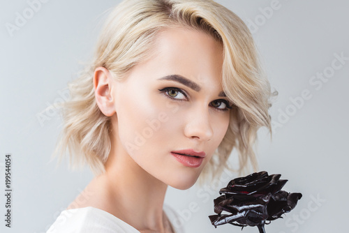 Fotografia portrait of attractive blonde girl with black rose, isolated on grey