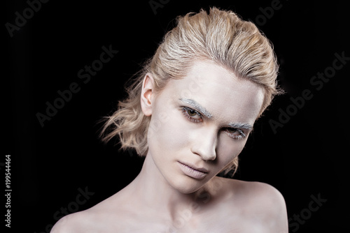 young blonde woman posing with white makeup, isolated on black