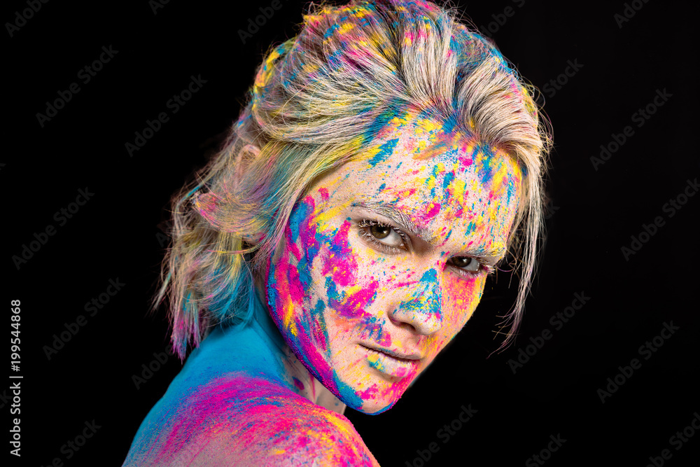 attractive fashionable girl posing in colorful holi powder, isolated on black