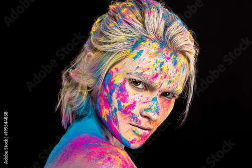 attractive fashionable girl posing in colorful holi powder, isolated on black