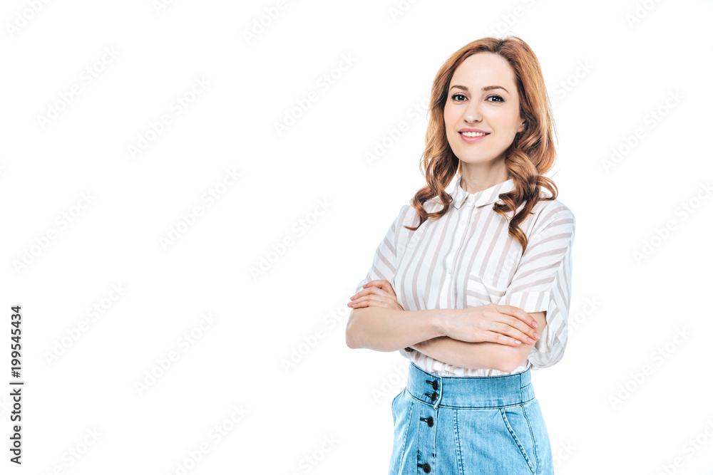 Fototapeta premium portrait of beautiful woman standing with crossed arms and smiling at camera isolated on white