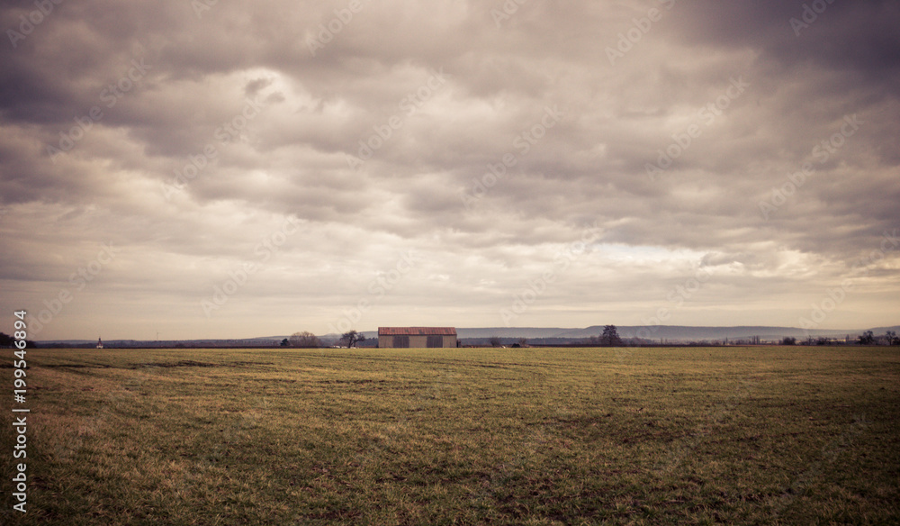 Landscape view to a barn under cloudy sky