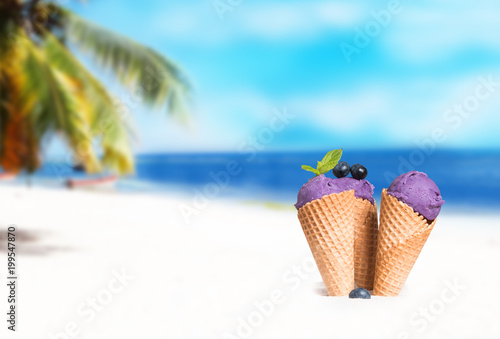Ice cream. Blueberry and Strawberry scoop in cone on sand beach © verca