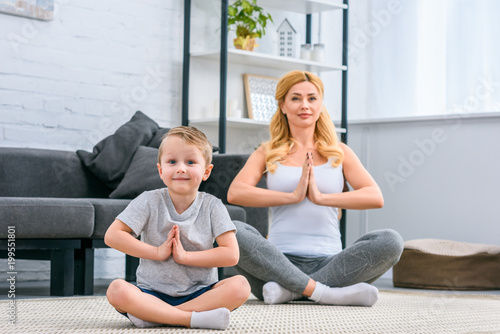 Photography Mother with little son practicing yoga in lotus position in living room