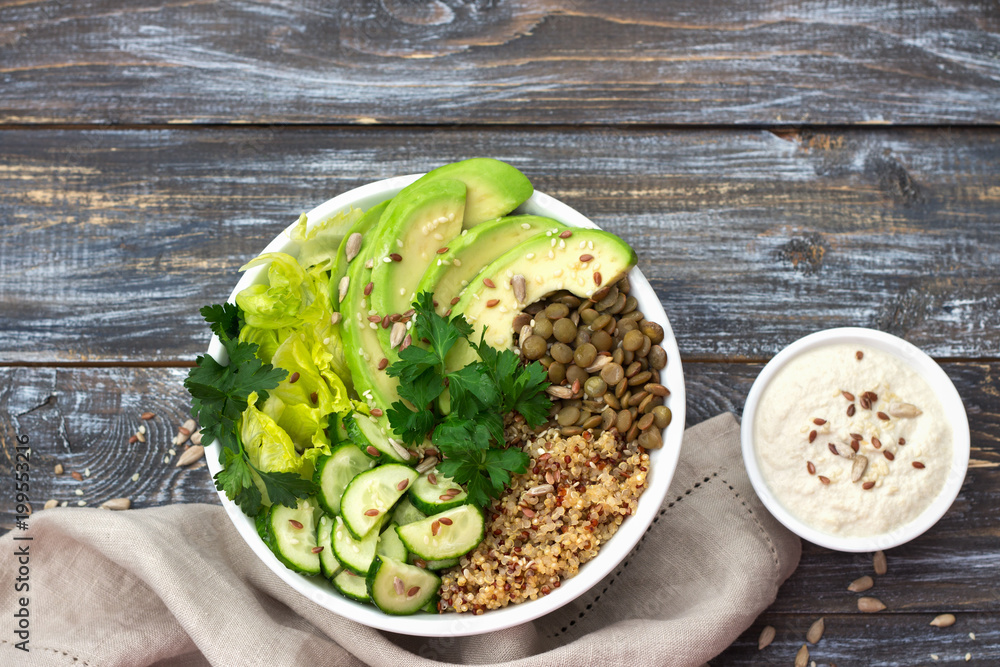 Green Buddha Bowl with lentils, quinoa, avocado, cucumber, fresh lettuce, herbs and seeds with tahini sauce. Delicious healthy balanced eating. On a wooden background, top view, free space Green Buddha Bowl with lentils, quinoa, avocado, cucumber, fresh lettuce, herbs and seeds with tahini sauce. Delicious healthy balanced eating. On a wooden background, top view, free space