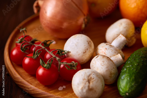 Vitamin fruits and vegetable collection with tomatoes cherry, mushrooms and red onions on a wooden background.