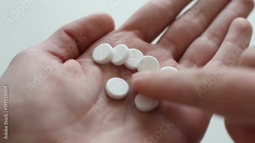 Man takes and shows pills vitamins or drugs tablets in hand