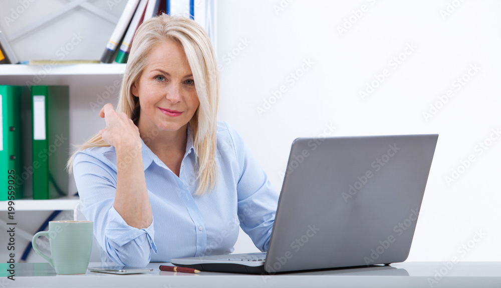 Beautiful business lady is looking at camera and smiling while working in office Beautiful business lady is looking at camera and smiling while working in office
