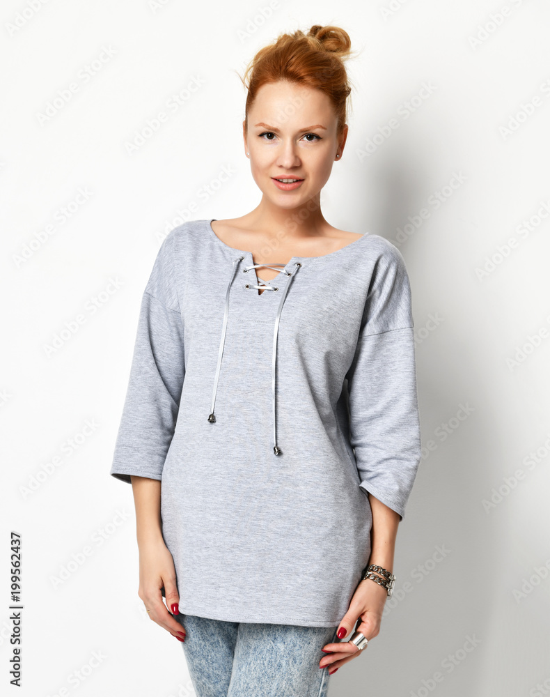 Young beautiful woman posing in new casual grey blouse looking down on a white Young beautiful woman posing in new casual grey blouse looking down on a white