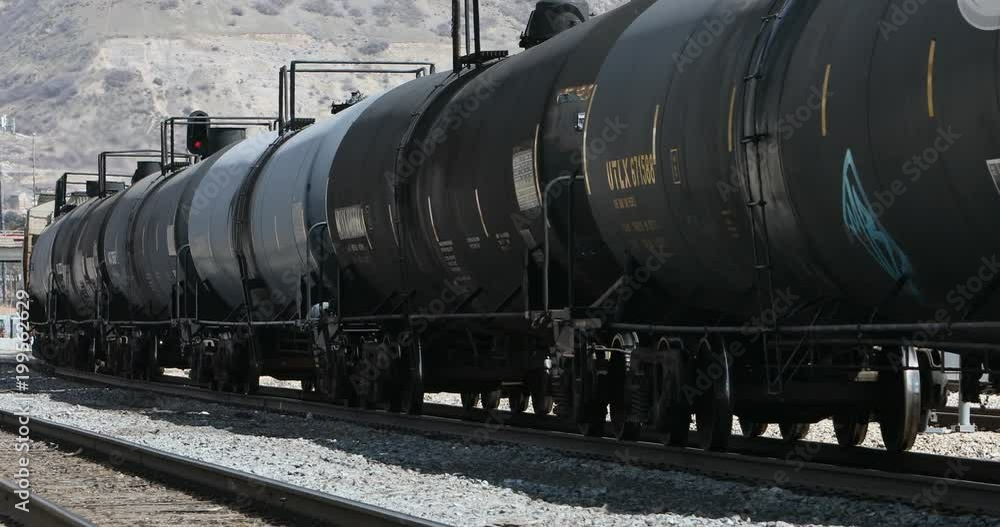 Railroad train oil tanker cars transportation. Cargo freight trail cars passing in urban city center. Food, liquid or oil fuel container. Heavy industrial commerce transportation. Graffiti. Railroad train oil tanker cars transportation. Cargo freight trail cars passing in urban city center. Food, liquid or oil fuel container. Heavy industrial commerce transportation. Graffiti.