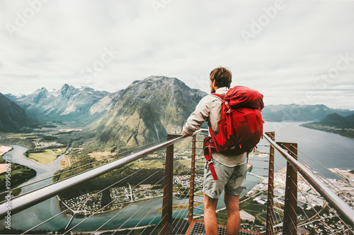 Adventurer man with red backpack enjoying mountains scenery Travel Lifestyle adventure vacations traveler standing alone on Rampestreken viewpoint in Norway photo