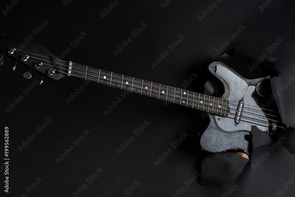 Obraz premium Background. Electric guitar through paper. Music instrument. Black electro-guitar.
