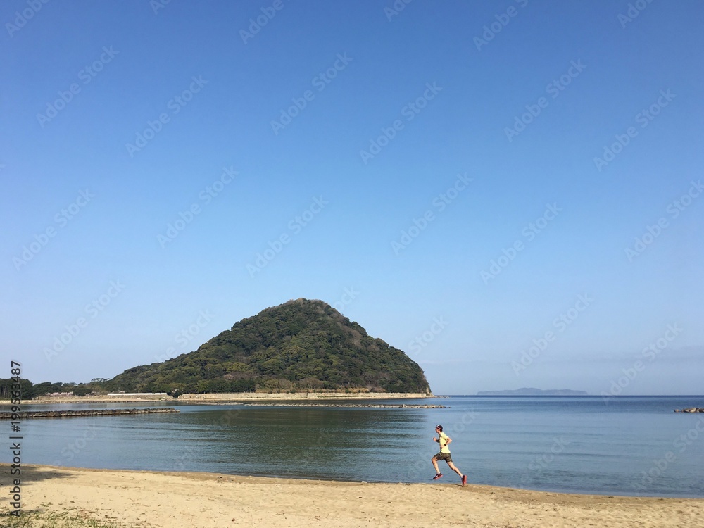 Man running on sandy beach with blue sky background - obrazy, fototapety, plakaty 