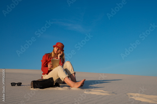 Dreaming young woman uses a tablet pc, internet in desert © sanechka