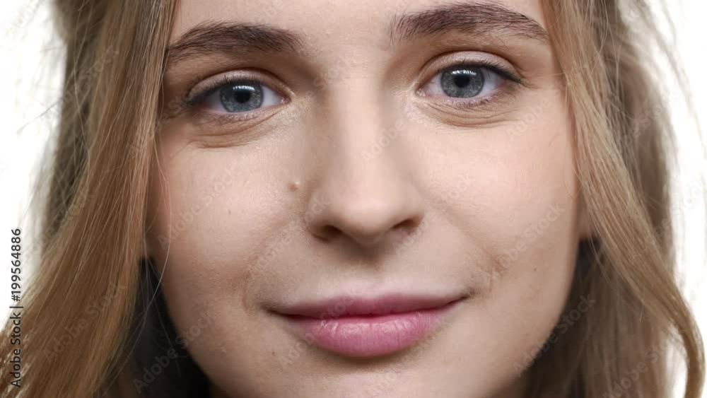 Extreme closeup portrait of lovely european woman 20s with curly brown hair and blue eyes looking on you with happy smile, isolated over white background. Concept of emotions Extreme closeup portrait of lovely european woman 20s with curly brown hair and blue eyes looking on you with happy smile, isolated over white background. Concept of emotions