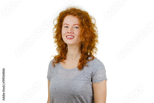 Portrait of cute redhead girl with curly hair in gray t-shirt, smiling looking at camera. Isolated on white background