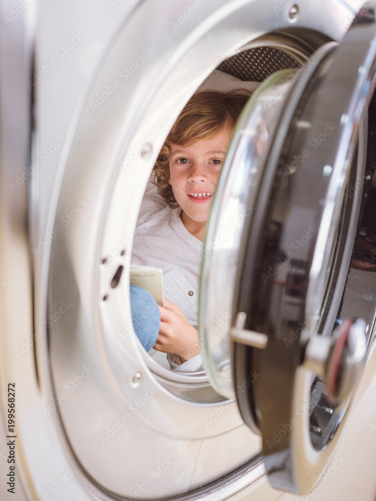 Boy reading book in laundry machine Boy reading book in laundry machine
