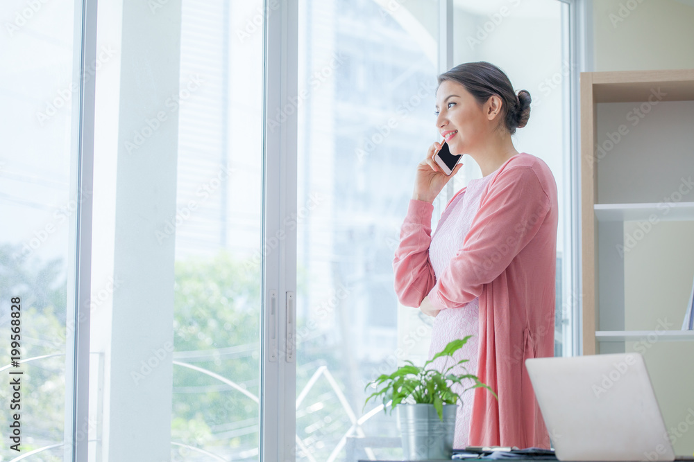 Obraz premium businesswoman talking on smartphone and standing in modern office