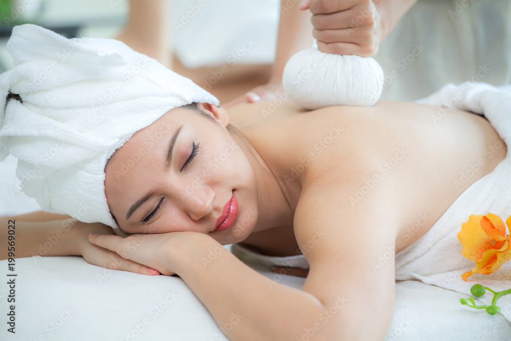 Beautiful young woman lying and relaxing treatment with herbal compresses in a spa enjoying and eyes closed